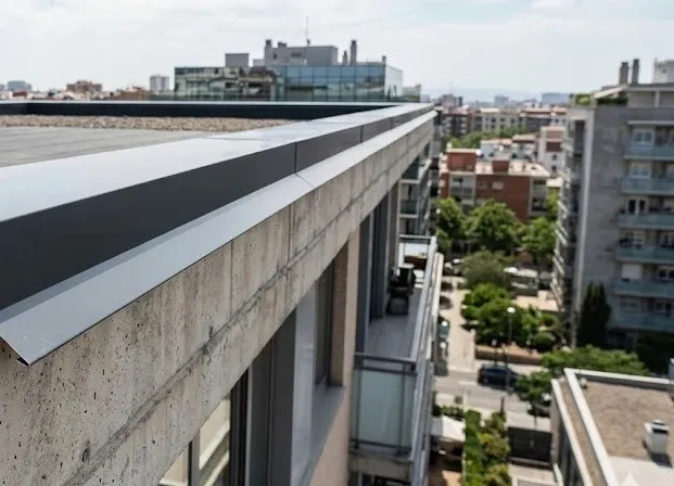 Cómo instalar goterones: Fotografía de los pretiles de una construcción con goterones de aluminio color gris.